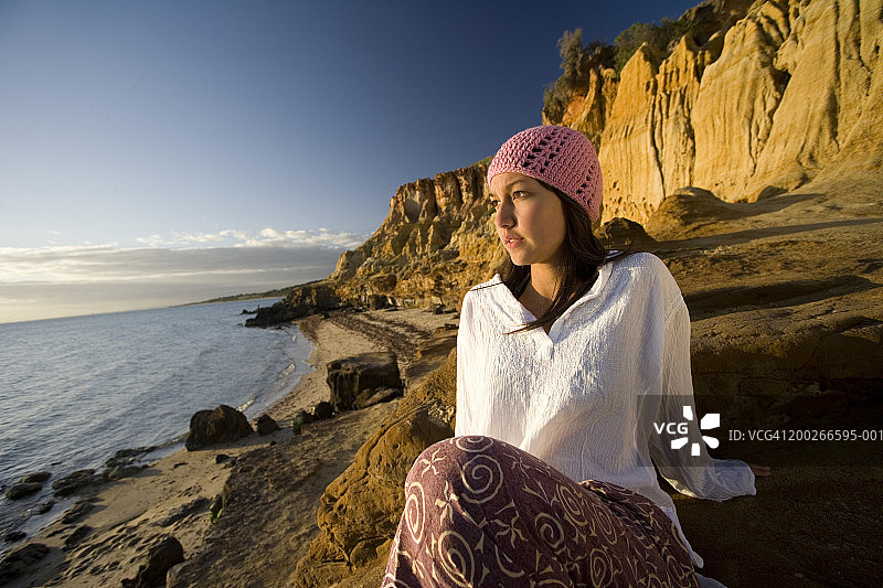 少女坐在岩石上眺望大海图片素材