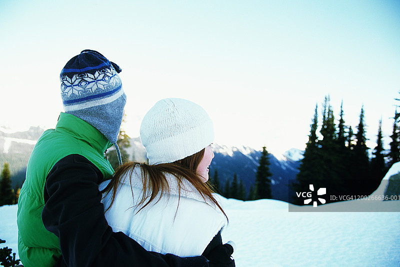 在雪山风景中拥抱的戴羊毛帽的情侣图片素材