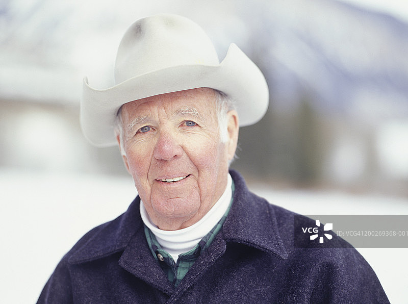 戴牛仔帽站在雪中的年长男人肖像图片素材
