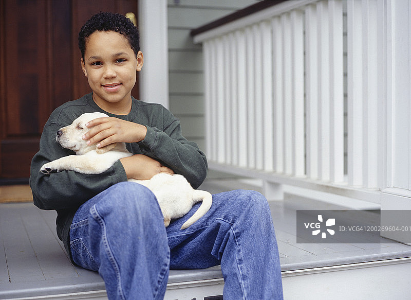 10-11岁男孩和黄色拉布拉多幼犬的肖像照图片素材