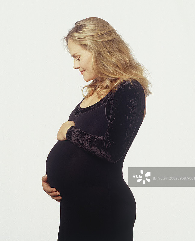 面带微笑，孕妇双手护着肚子图片素材