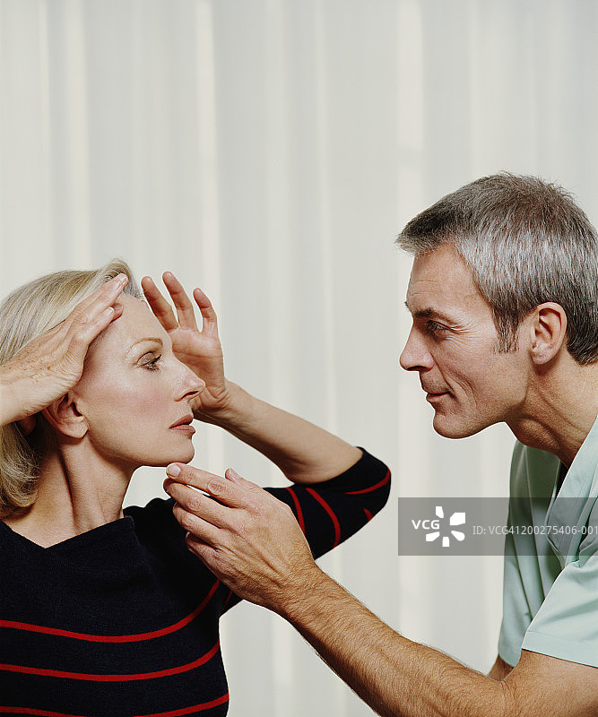 美容外科医生检查中年妇女的面部轮廓图片素材