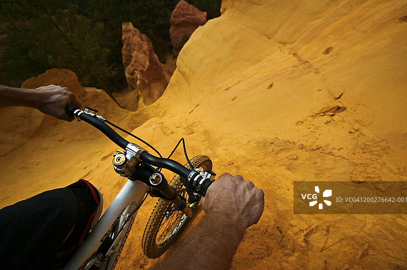 男人在山腰上紧握自行车的车把，高空俯视图片素材