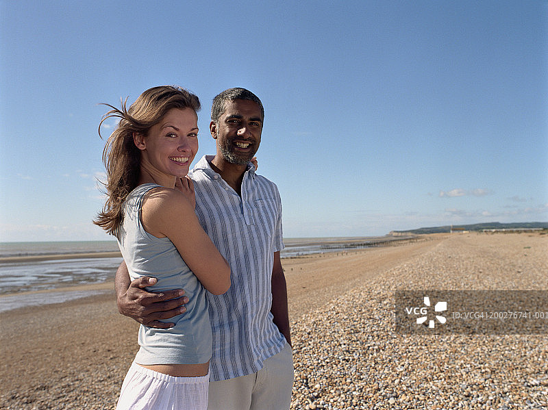 在鹅卵石海滩上微笑的情侣肖像图片素材
