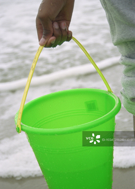 在海滩拿着塑料桶的女孩（10-12岁），桶的特写图片素材