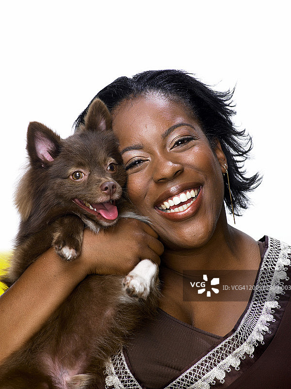 抱着博美犬微笑的年轻女人图片素材