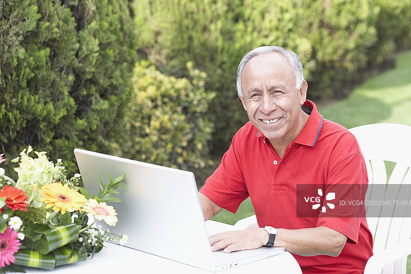 在花园里使用笔记本电脑的老年男人 портрет图片素材