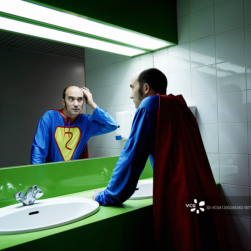 身穿超级英雄服装的男人照镜子图片素材