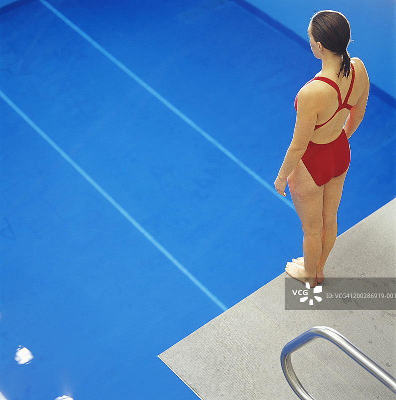 站在泳池上方跳板上的女游泳运动员图片素材