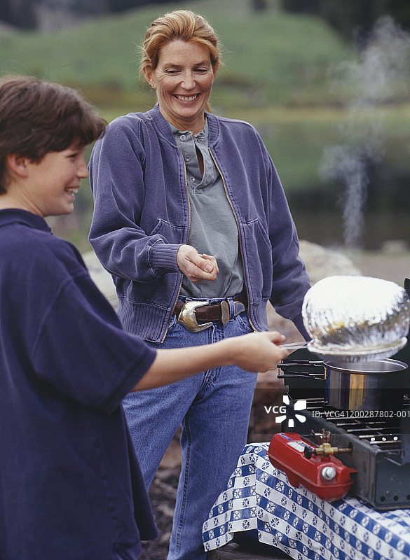 母亲和十几岁的儿子（13-14岁）在野营炉上制作爆米花图片素材