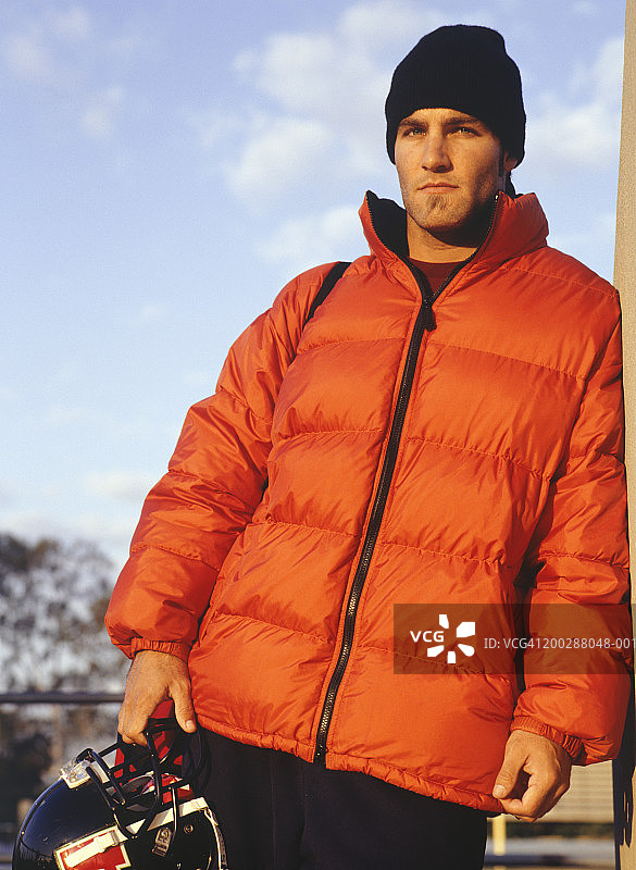 站在体育场里，拿着橄榄球头盔的男人，低角度拍摄图片素材