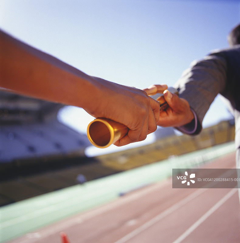 两名男子在体育场传递金色接力棒特写图片素材