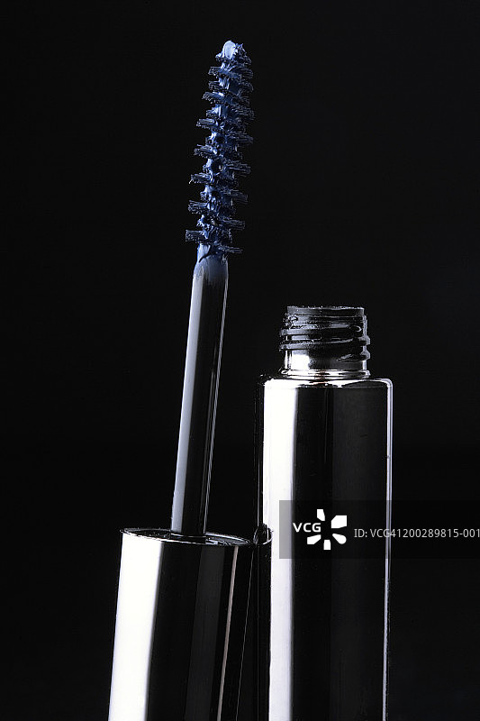 打开的蓝色睫毛膏刷头和睫毛膏，黑色背景特写图片素材