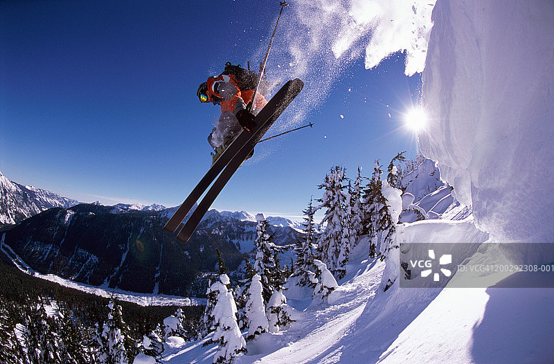 男人从雪檐跳下，手持滑雪板，低角度视角图片素材