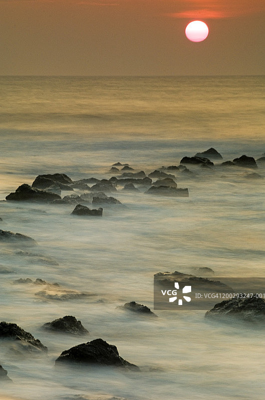 日落时海洋中的岩石图片素材