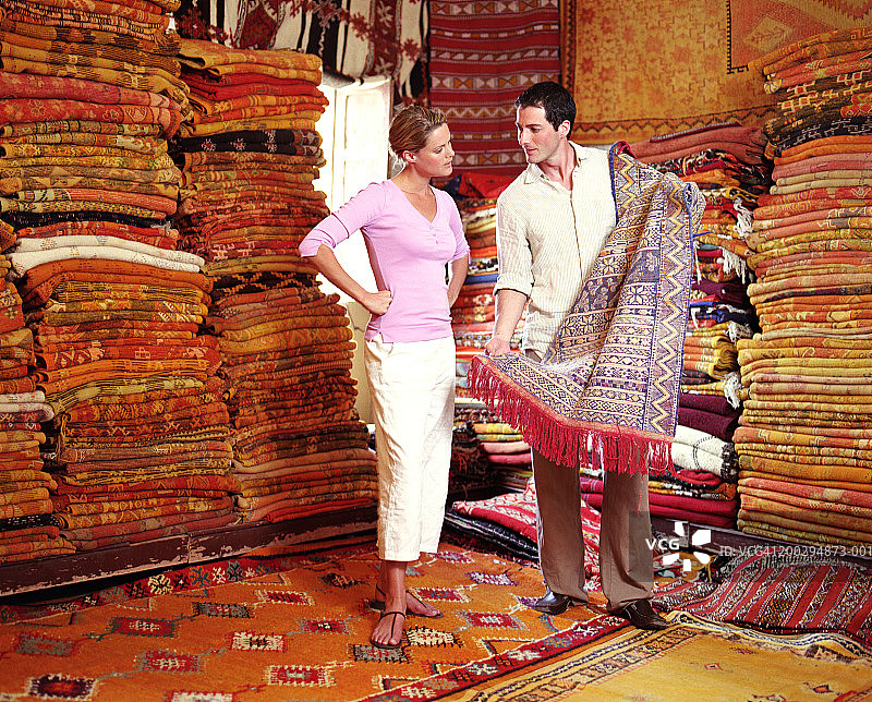 女人看着在地毯店里拿着地毯的男人图片素材