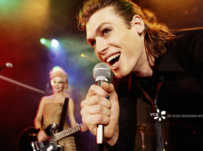 男人对着麦克风唱歌，女人弹着电吉他图片素材