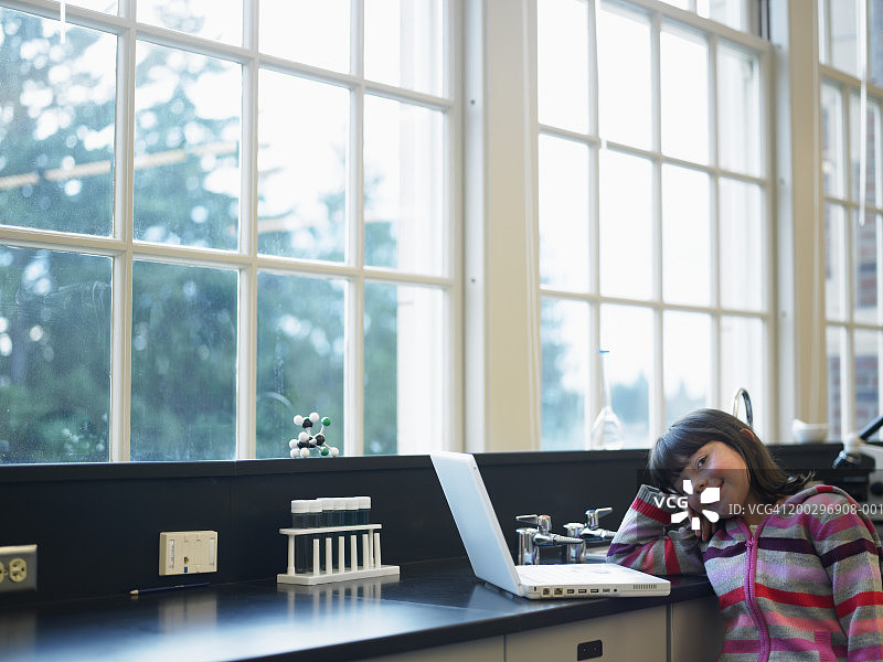 在实验室里，女儿(6-8岁)用笔记本电脑，手托着头图片素材