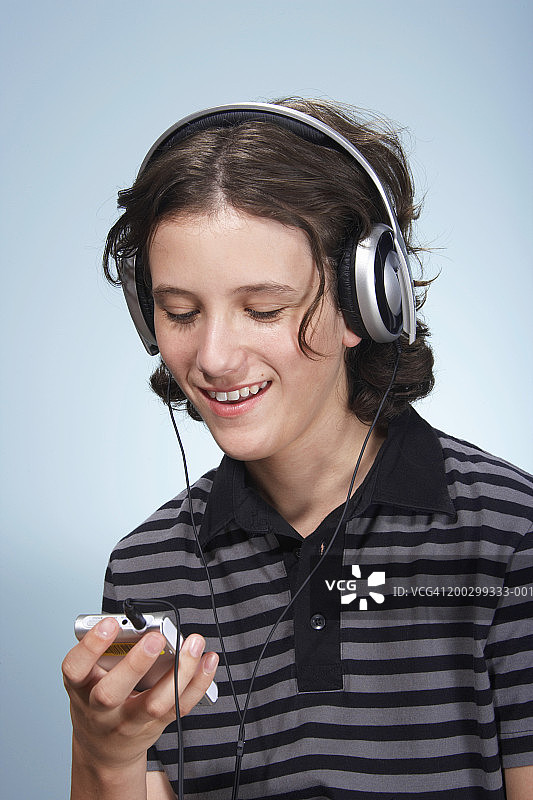 少年穿着条纹上衣听便携式播放器图片素材