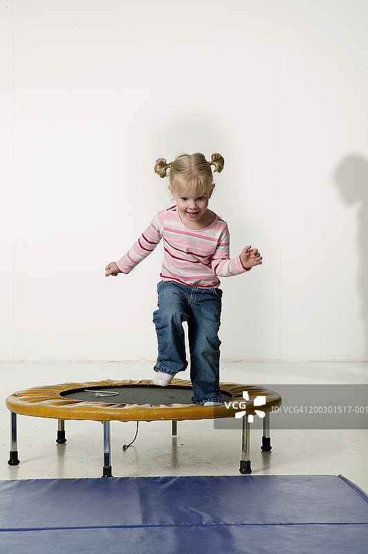 在小型蹦床上跳跃的小女孩（6-7岁）图片素材