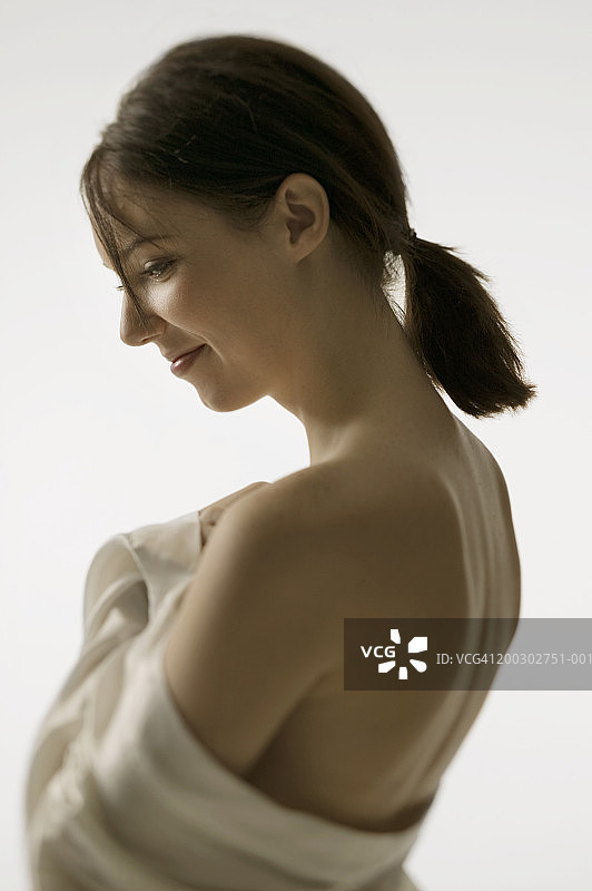 在影棚中袒露肩膀的深色头发年轻女人肖像图片素材