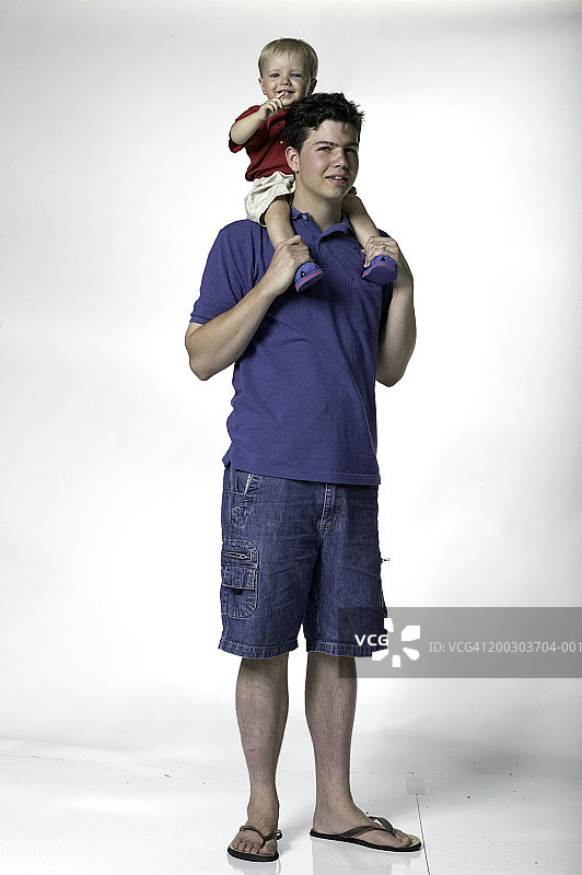 肩上扛着男孩（18-21个月大）的年轻人肖像图片素材