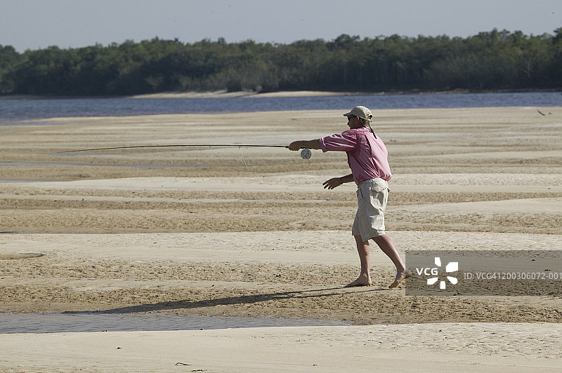 在河岸边抛竿钓鱼的男人图片素材