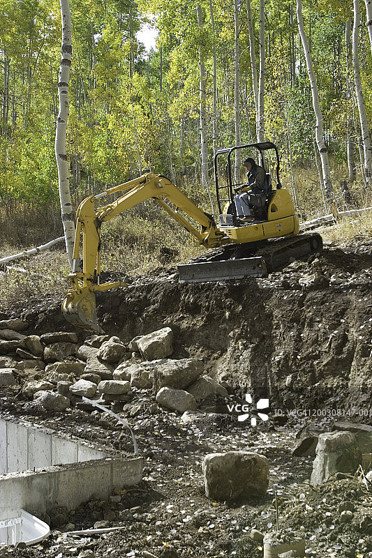 男子在黄色挖掘机上工作图片素材