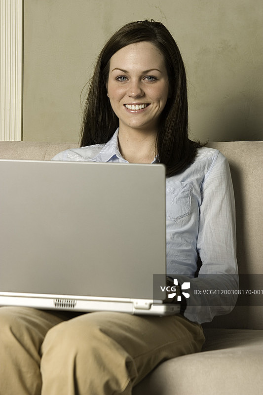 女人坐在沙发上使用笔记本电脑的肖像图片素材