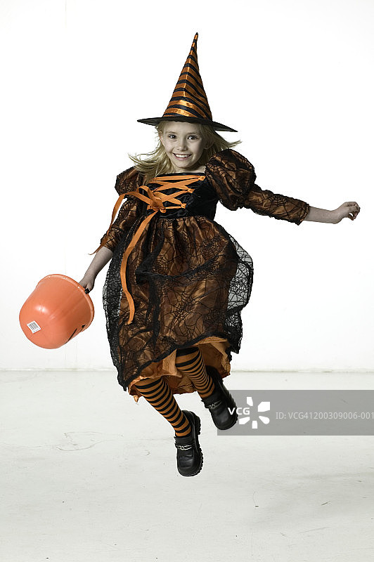 穿着女巫服装，在工作室跳跃的女孩（6-7岁）图片素材