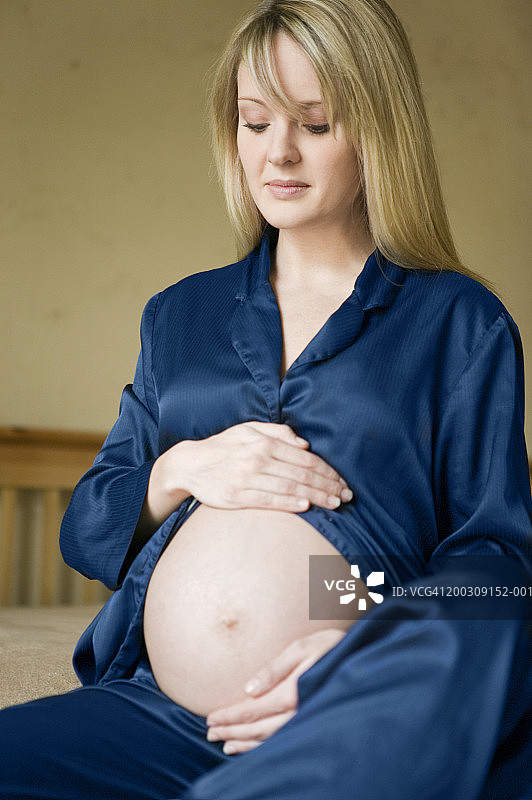 孕妇在卧室里触摸肚子图片素材