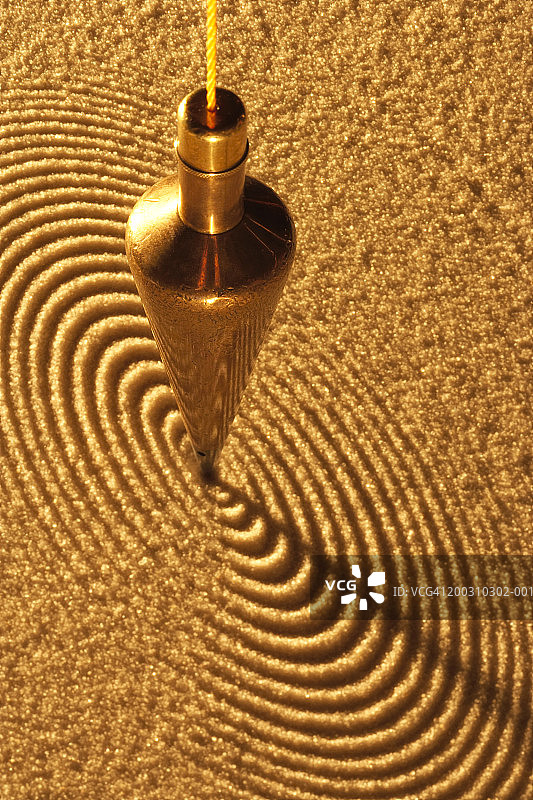 黄铜摆在沙地上画圆圈，高角度视图图片素材