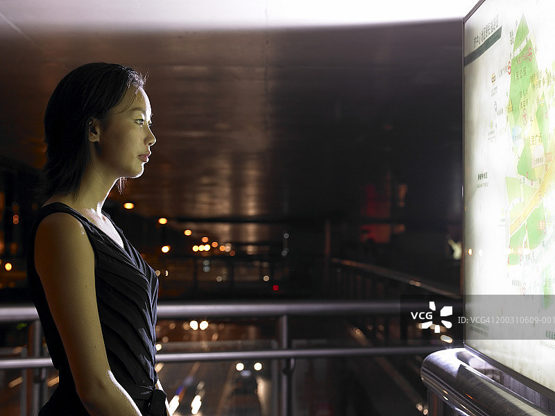 夜晚看地图的年轻女人（长曝光，侧视图）图片素材