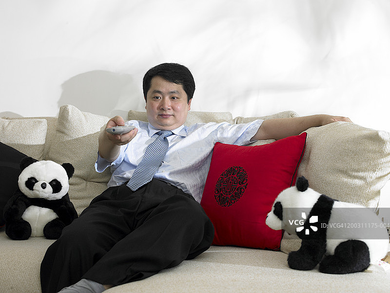 男人在沙发上指向电视遥控器图片素材