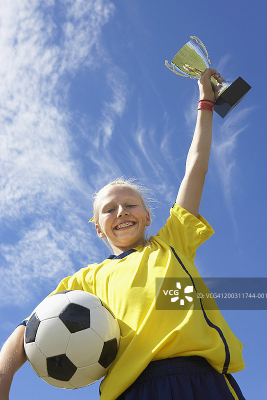 手持足球和奖杯的女孩（10-12岁）低角度肖像图片素材