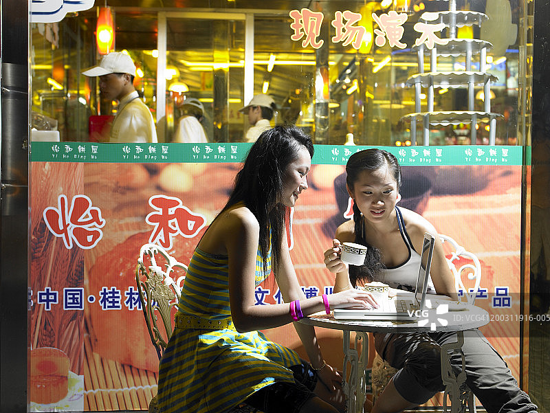 少女与年轻女人在咖啡馆使用笔记本电脑图片素材