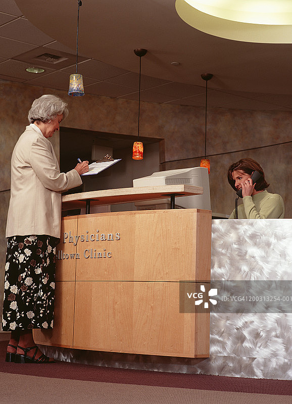 年长的女人在诊所接待处填写表格图片素材