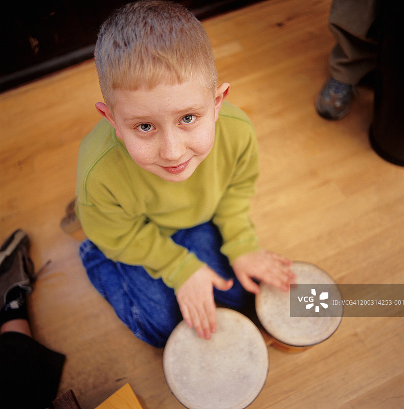 男孩（8-9岁）演奏邦戈鼓，肖像，仰视图片素材