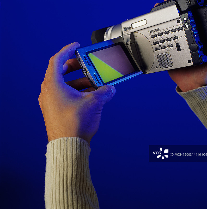 男人使用数码摄像机在演播室摆姿势，手部特写图片素材