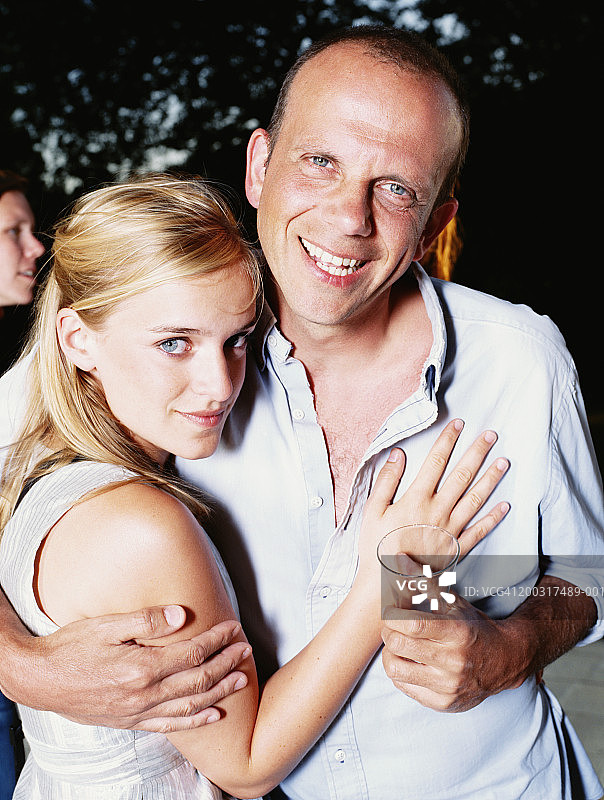 男人在户外拥抱微笑的年轻女人，肖像图片素材