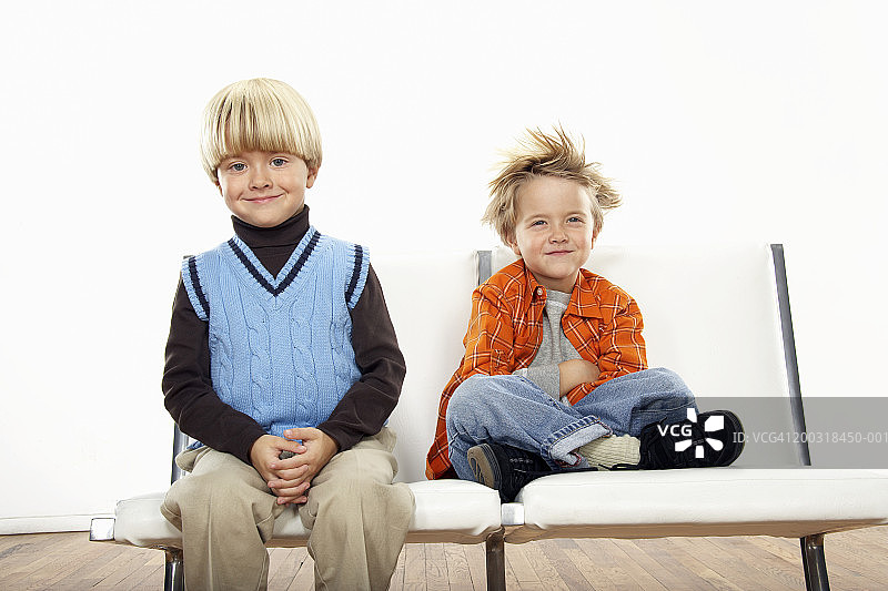 微笑的双胞胎男孩肖像（3-5岁），穿着正装和休闲装图片素材