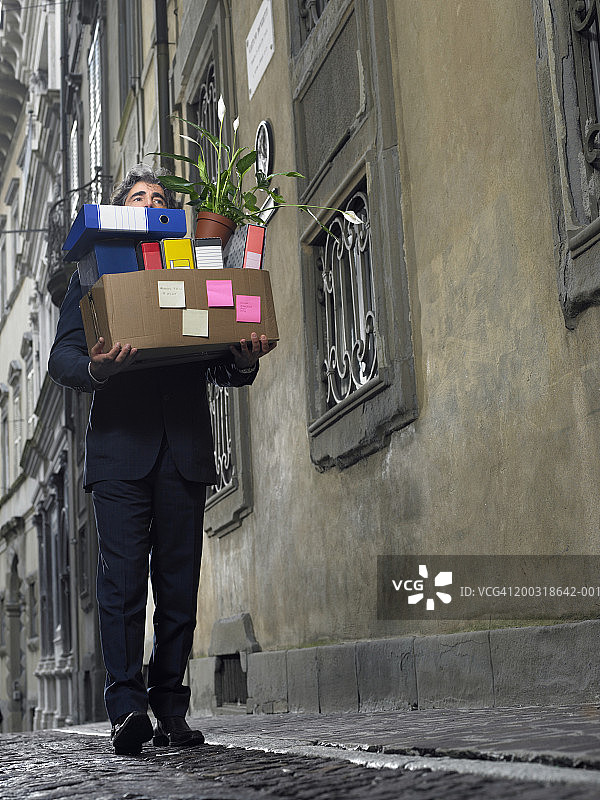 在街上携带一箱办公室文件的中年商人图片素材