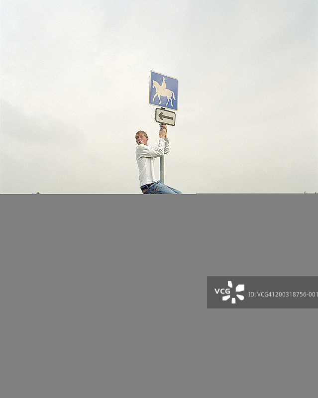 男人攀爬路标图片素材