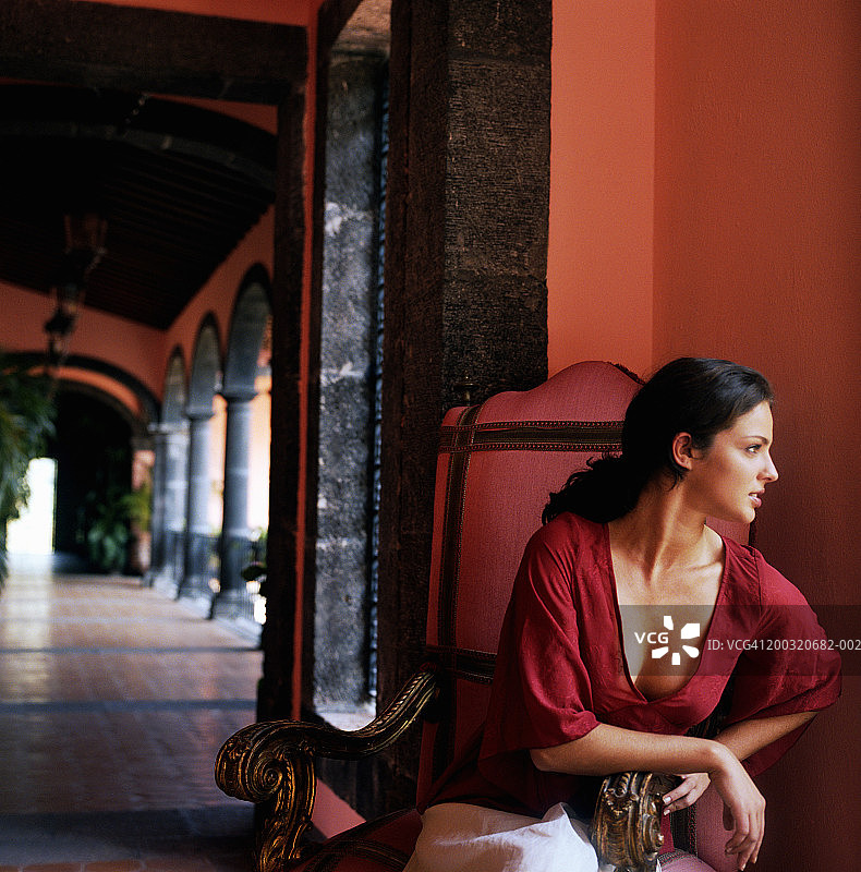 年轻女子坐在红色椅子上看向一侧，背景是游戏厅图片素材