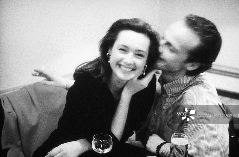 男人在女人耳边低语微笑（黑白照片）图片素材