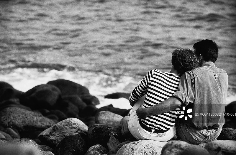 情侣坐在卵石滩上，后视图（黑白）图片素材