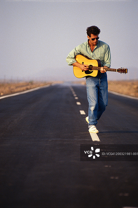 年轻男子在高速公路上弹吉他图片素材