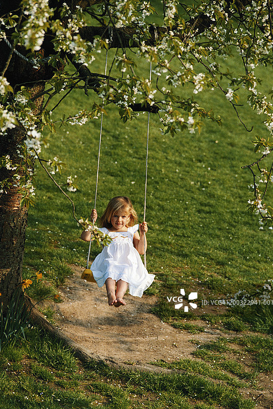 在田野里荡绳秋千，微笑的女孩（3-4岁）图片素材