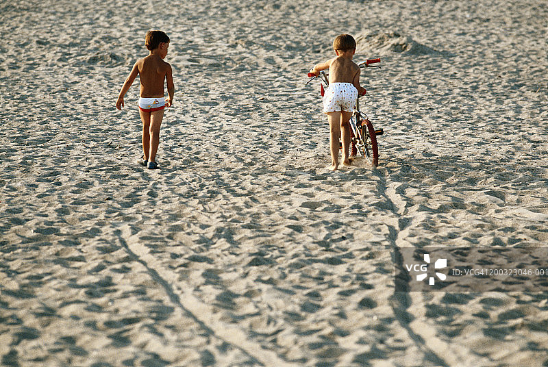 孩子们骑着自行车在沙滩上，后视图图片素材