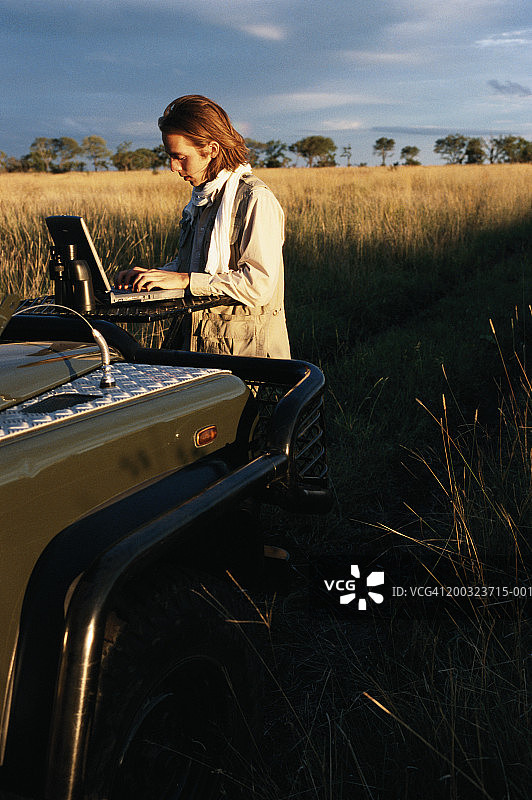 在田野里使用笔记本电脑的越野车男人图片素材